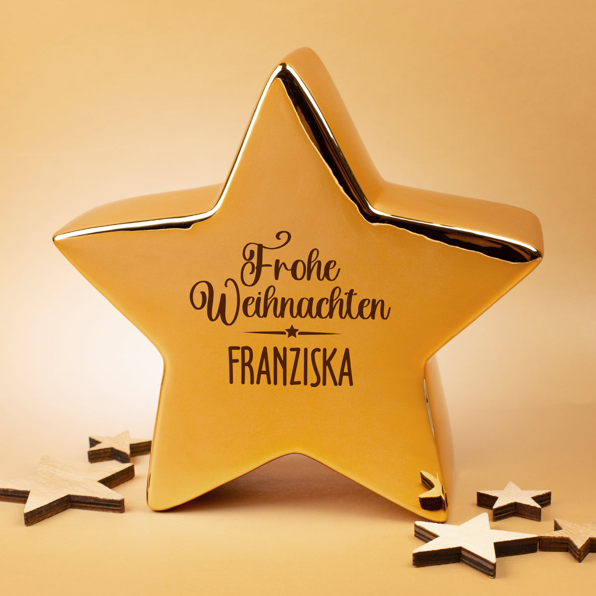 Leonardo Keramikstern in Gold mit Weihnachtsmotiv und Namen, fotografiert im warmen Licht