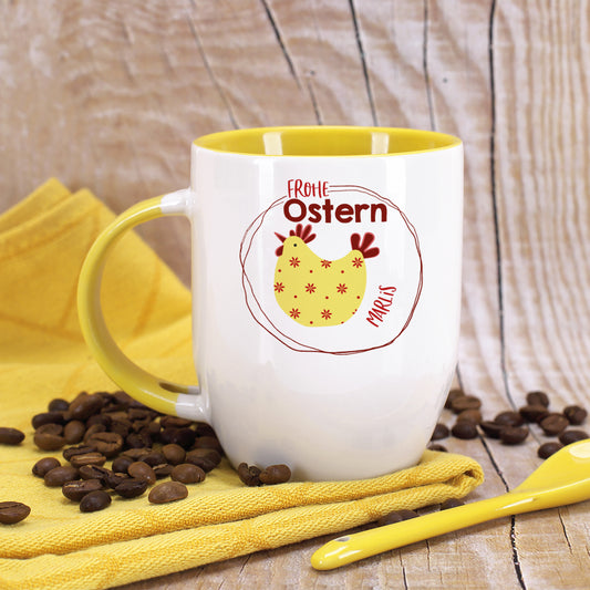 Personalisierte Löffeltasse „Frohe Ostern“ mit gelbem Huhn-Motiv, Name Marlis und gelbem Löffel auf Holztisch