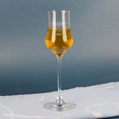 Leonardo Grappaglas mit Gravur „Jürgen“ – gefüllt mit goldfarbenem Grappa, auf blauem Hintergrund.