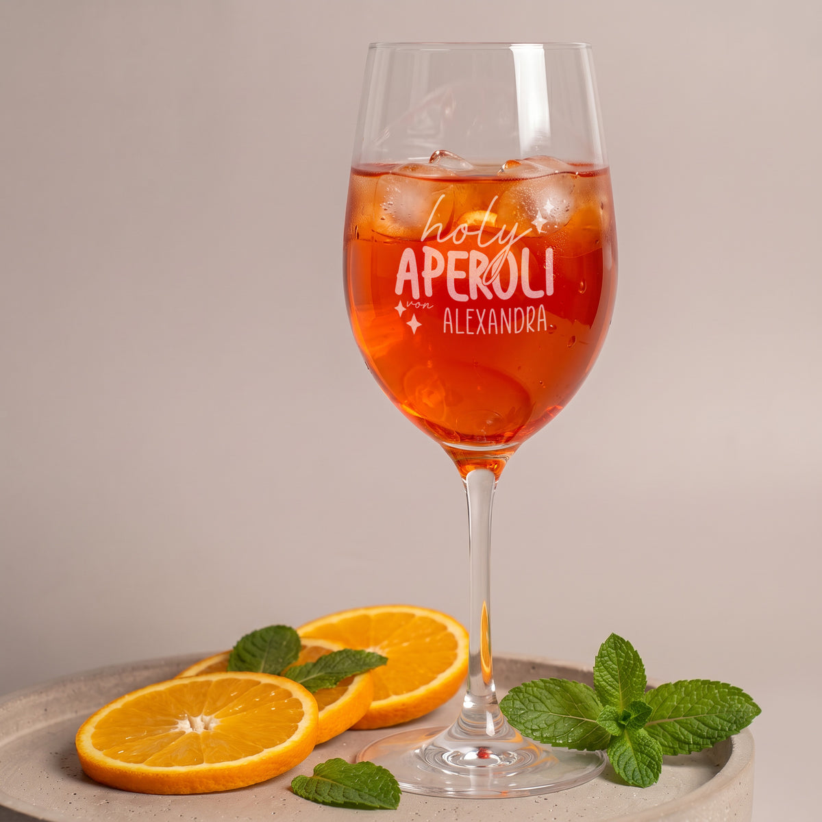 Personalisiertes Holy Aperoli Glas mit Wunschname, gefüllt mit Aperitif und Eiswürfeln