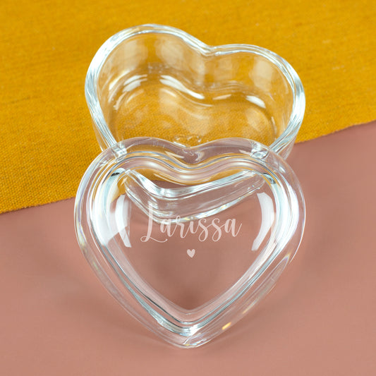 Personalisierte Leonardo Herzdose aus Glas mit Gravur des Namens Larissa und Herzmotiv auf gelbem Tuch