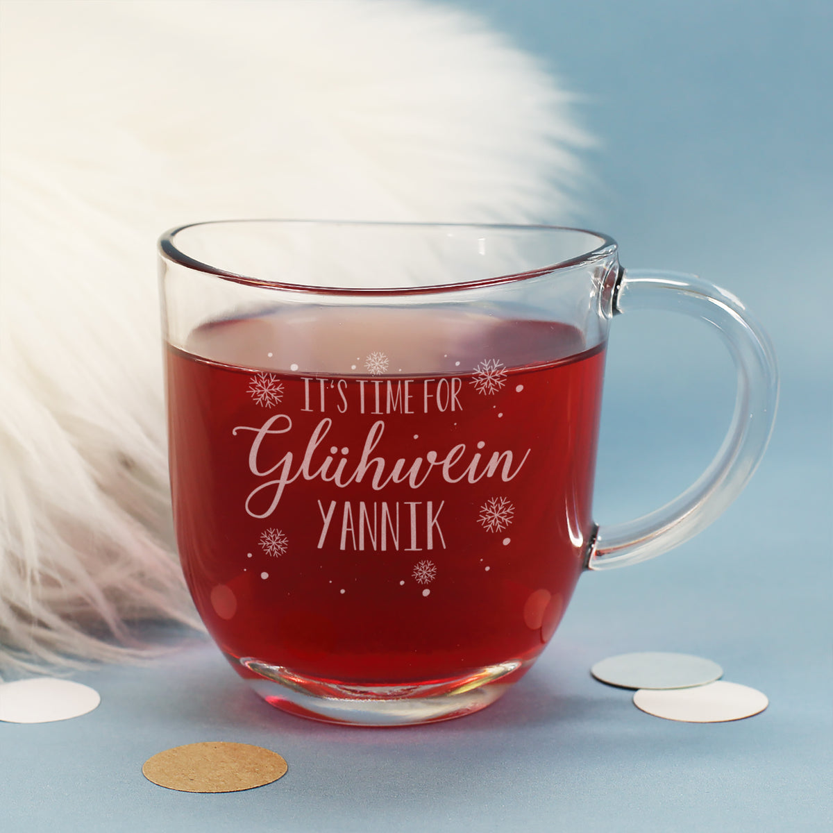 Personalisierte Glühwein-Tasse mit Namensgravur „Yannik“ vor weißem Fellhintergrund