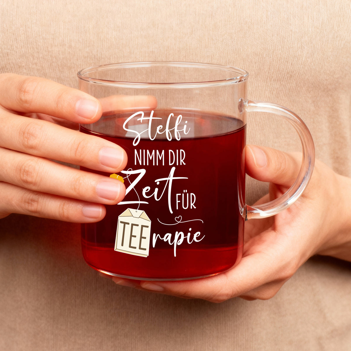 Teeglas mit personalisiertem TEErapie-Spruch und Name, in Händen gehalten