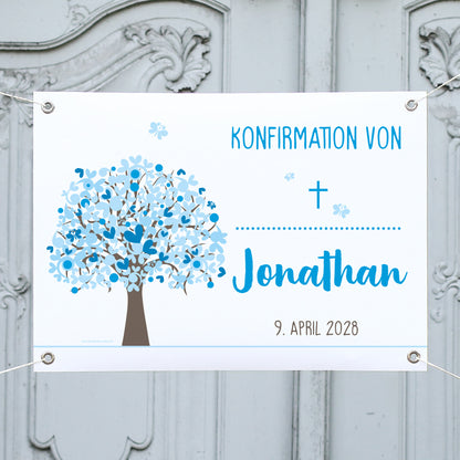 Personalisierbares Banner zur Konfirmation mit Lebensbaum in Blautönen. Text: „Konfirmation von Jonathan – 9. April 2028“. Aufgehängt vor einer grauen Holztür, mit Kreuzsymbol und blauen Schmetterlingen.