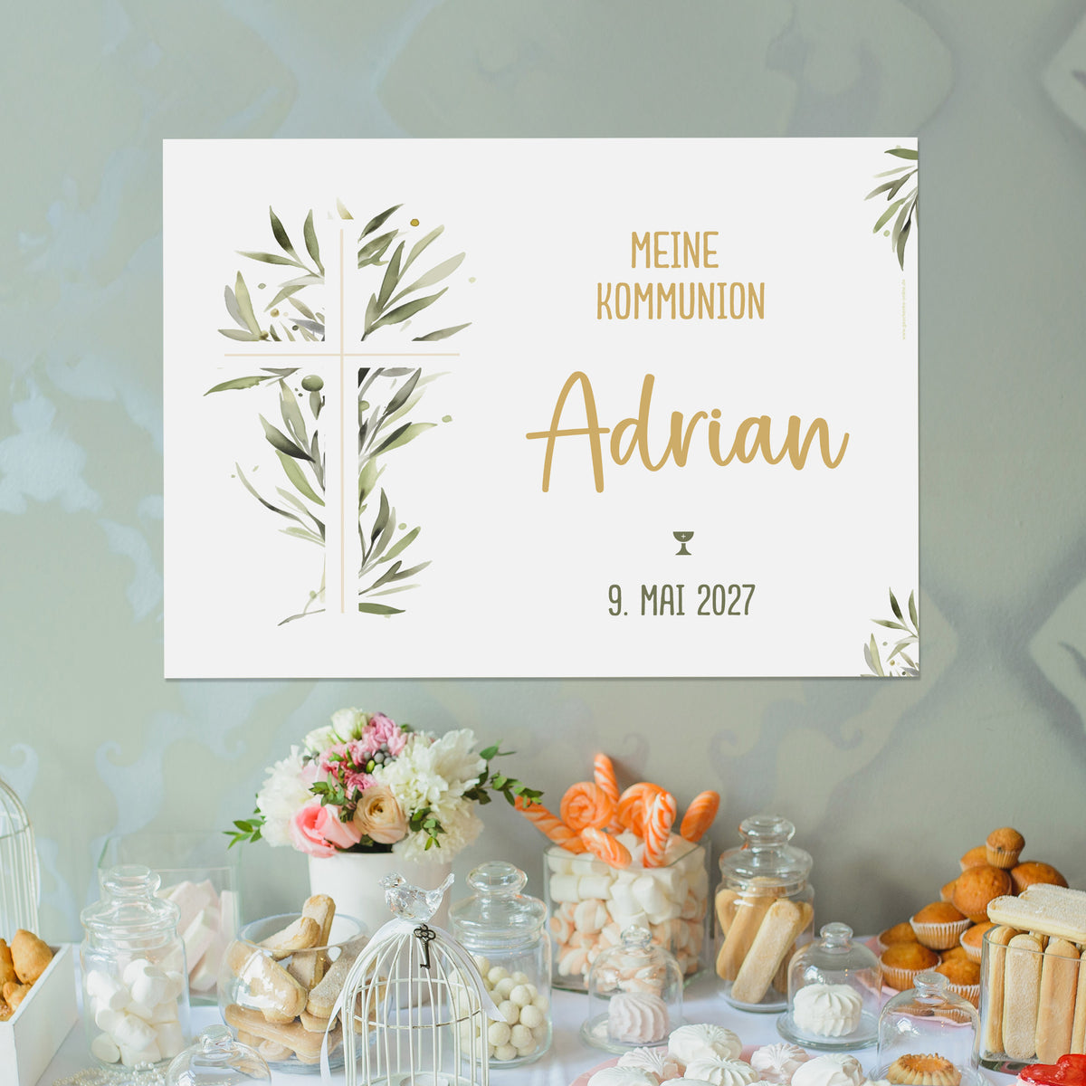 Personalisierbares Banner mit Kreuz und Ölzweigen über einem Sweet Table. Text: „Meine Kommunion – Adrian – 9. Mai 2027“. Christliches Dekoelement im festlich gedeckten Raum.