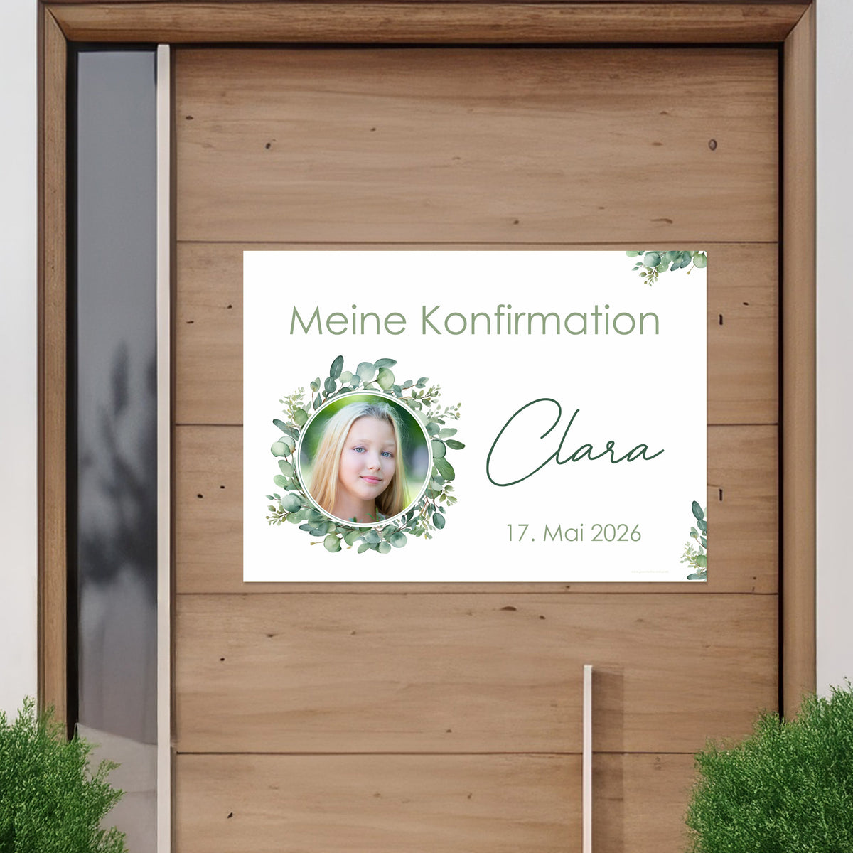 Banner mit Foto eines Mädchens im Eukalyptuskranz an einer Holztür befestigt. Text: „Meine Konfirmation – Clara – 17. Mai 2026“. Feierliche Dekoration für christliche Anlässe.