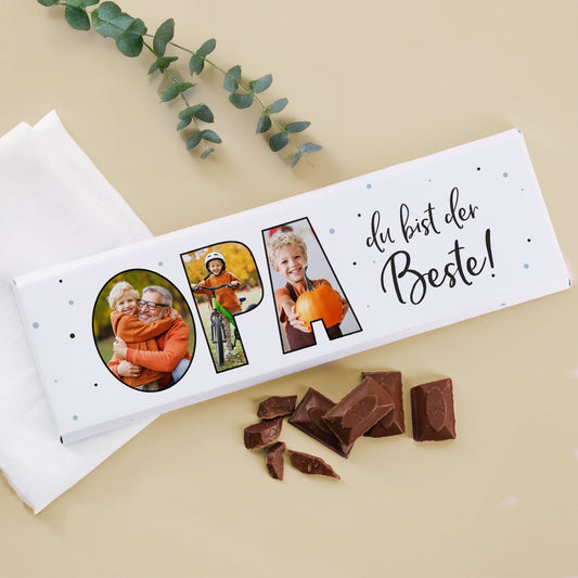 XXL Schokoladentafel „Opa du bist der Beste!“ mit 3 personalisierten Fotos und Milchschokolade-Stücken daneben, dekoriert mit Eukalyptuszweig