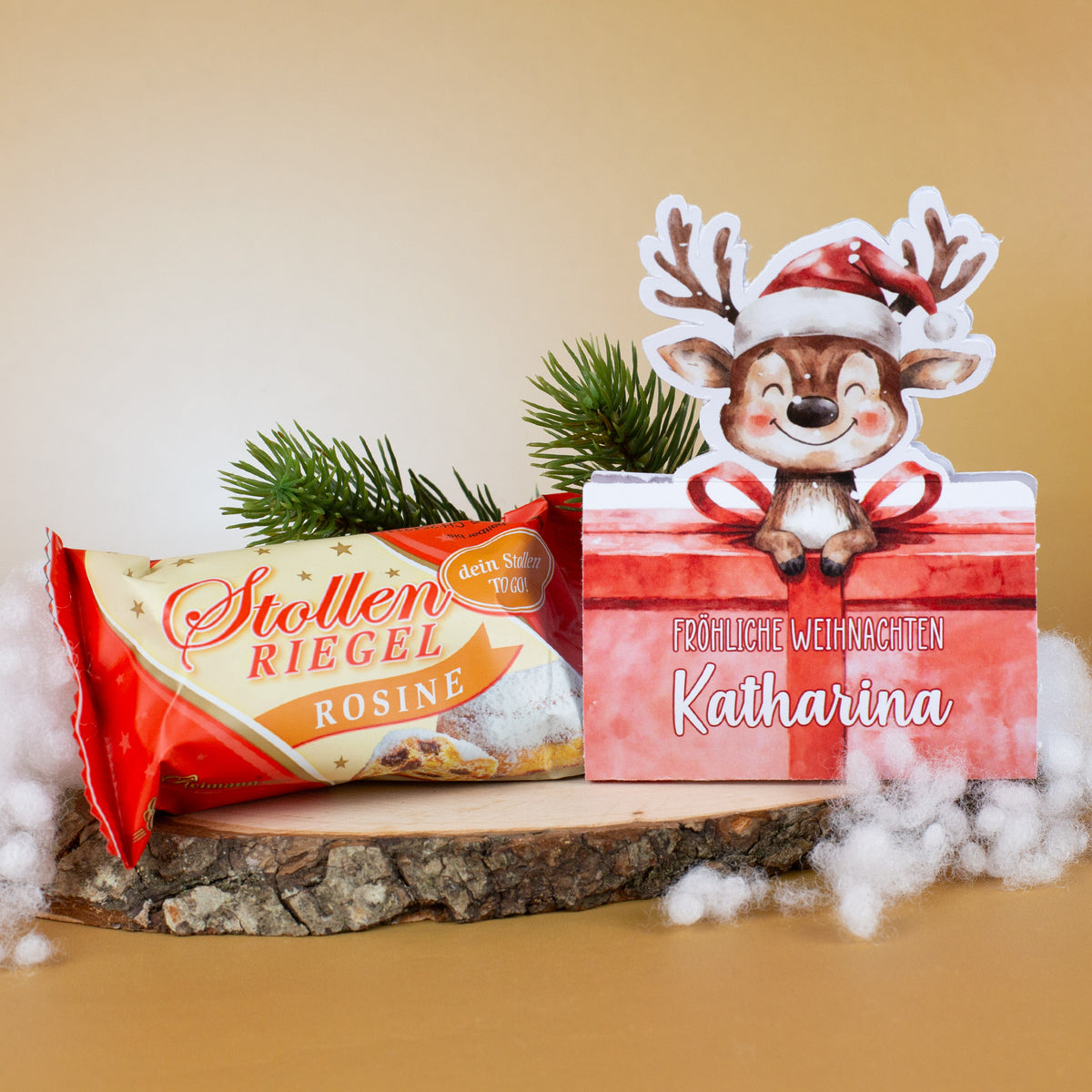 Mini-Stollen „Rosine“ neben Rentier-Geschenkverpackung mit personalisiertem Namen Katharina, auf Holzscheibe arrangiert.