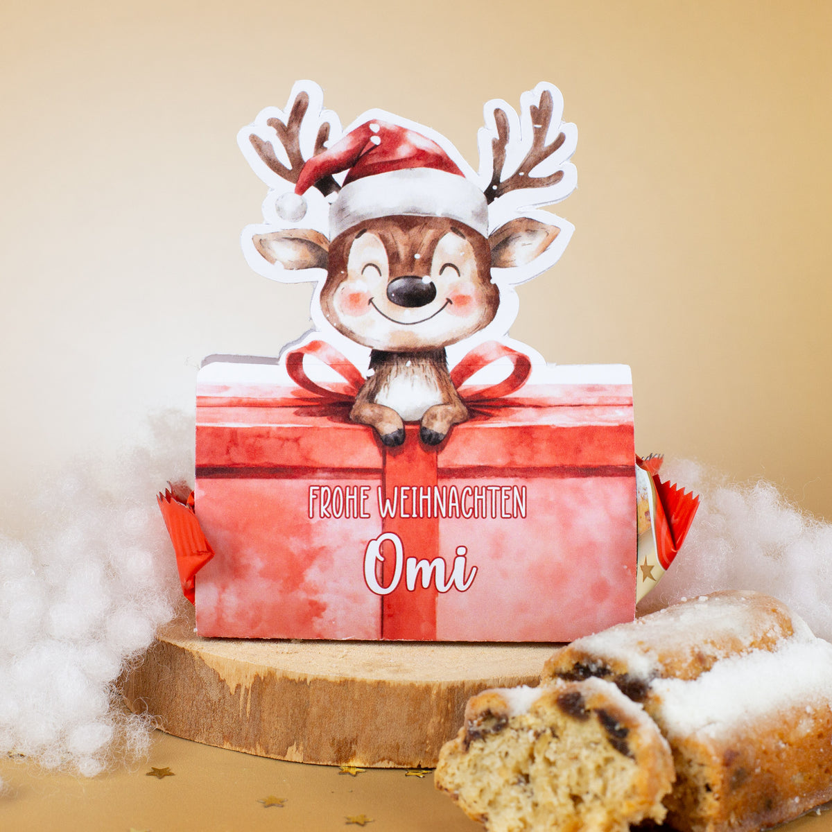 Rentier-Mini-Stollen mit personalisierter Verpackung – Aufdruck „Frohe Weihnachten Omi“, dekorativ auf Holzscheibe mit Stollenstücken und Kunstschnee.