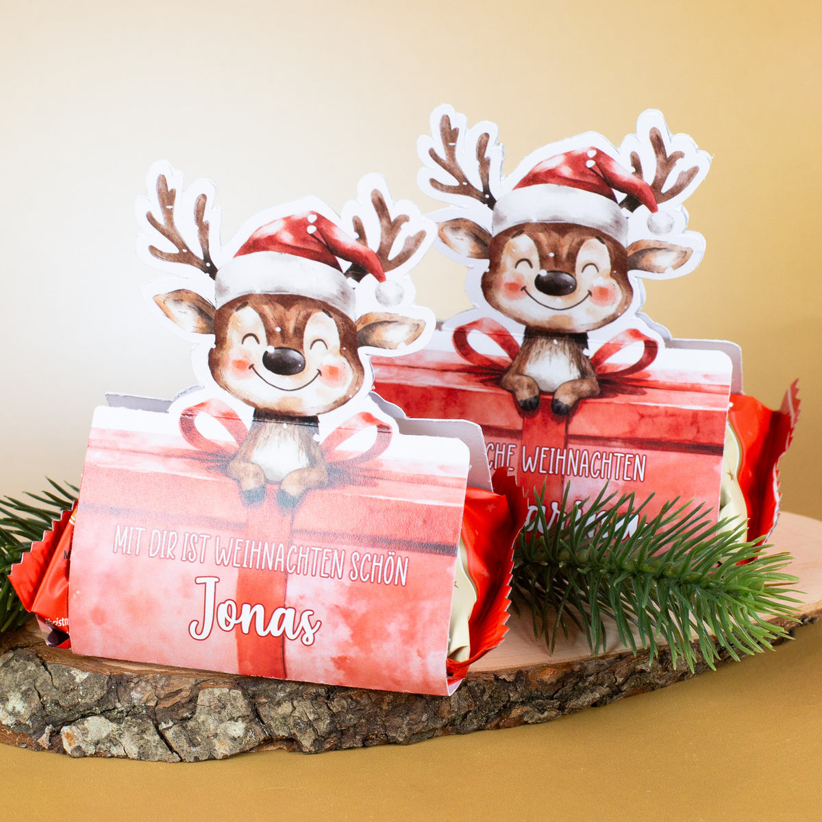 Zwei Mini-Stollen-Verpackungen mit Rentier-Motiv, personalisiert mit dem Namen Jonas, dekoriert mit Tannenzweig.