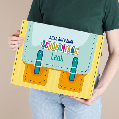 Große gelbe Geschenkverpackung zum Schulanfang mit Wunschname, von einer Person gehalten