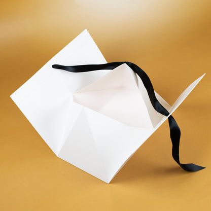 Geöffnete weiße Geschenkverpackung mit schwarzem Satinband, Innenansicht der Box