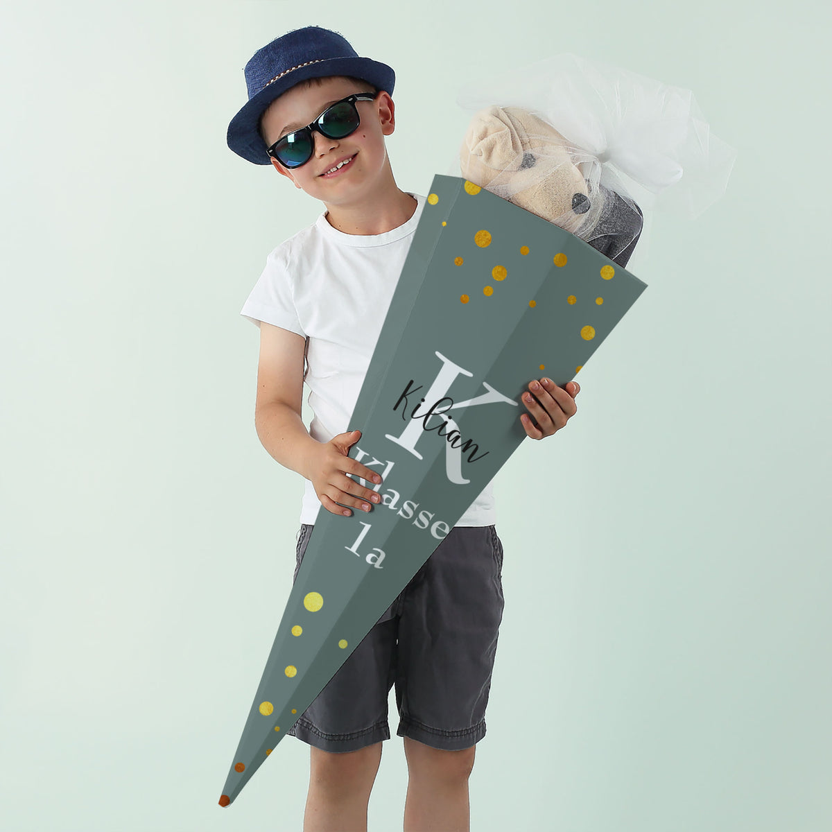 Junge mit dunkelgrüner Schultüte, personalisiert mit „Kilian“ und Klassenangabe