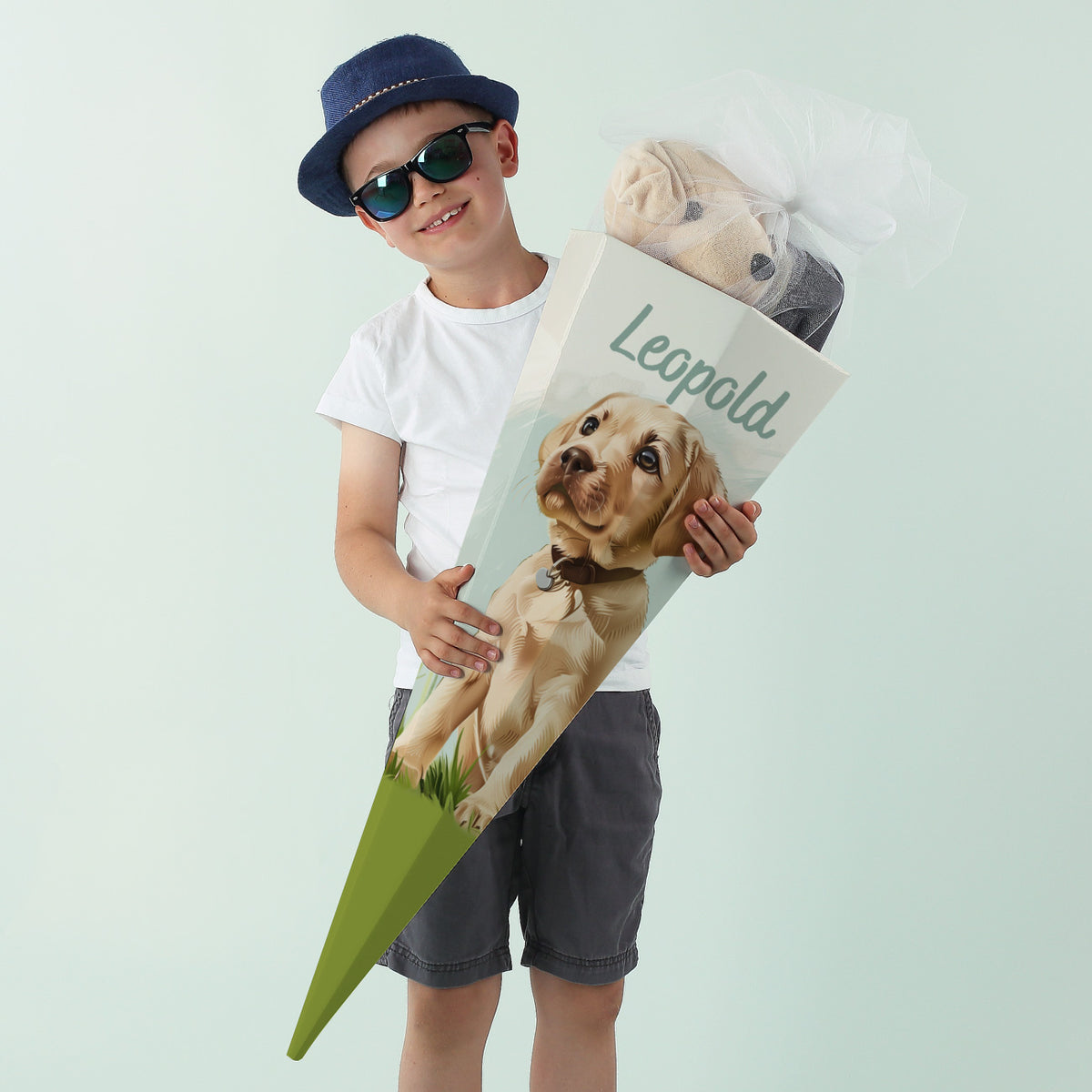 Mädchen mit Brille posiert fröhlich mit Hundeschultüte zur Einschulung
