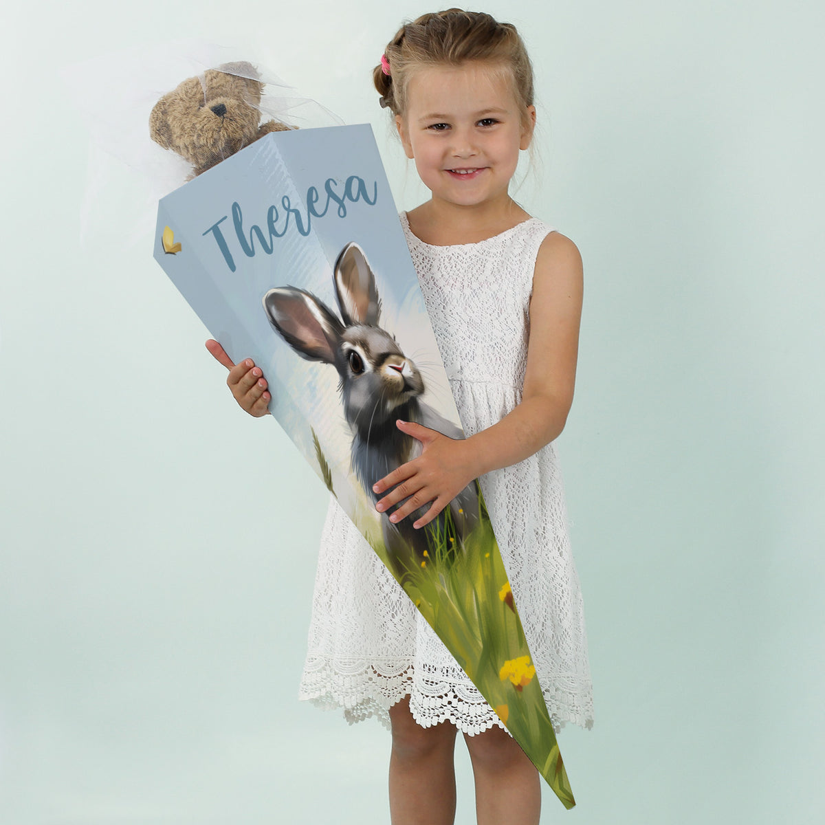 Mädchen mit weißem Kleid und personalisierter Hasen-Schultüte mit dem Namen „Theresa“