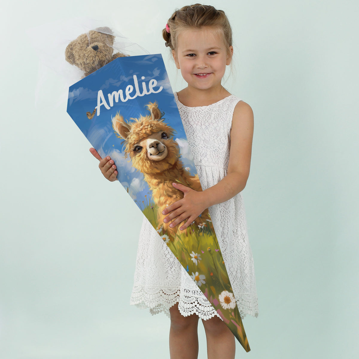 Mädchen im weißen Kleid hält eine Schultüte mit Alpaka-Motiv und dem Namen „Amelie“