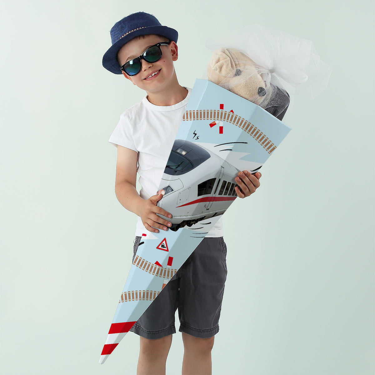 Junge mit Sonnenbrille hält ICE-Schultüte mit Stofftier