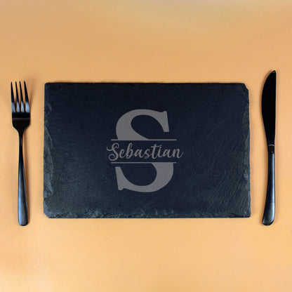 Personalisierte Schieferplatte mit Gravur „S“ und Name Sebastian, rechteckige Platte mit schwarzem Besteck auf orangem Hintergrund
