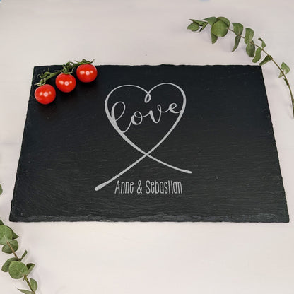 Schieferplatte mit Gravur „love“ in Herzform und „Anne & Sebastian“, dekoriert mit Tomaten und Eukalyptuszweig – auf hellem Untergrund