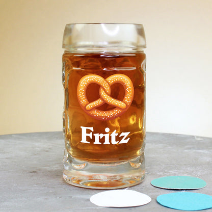 Mini-Bierkrug (4 cl) mit Brezel-Motiv und Name Fritz, stehend auf Tisch mit buntem Konfetti