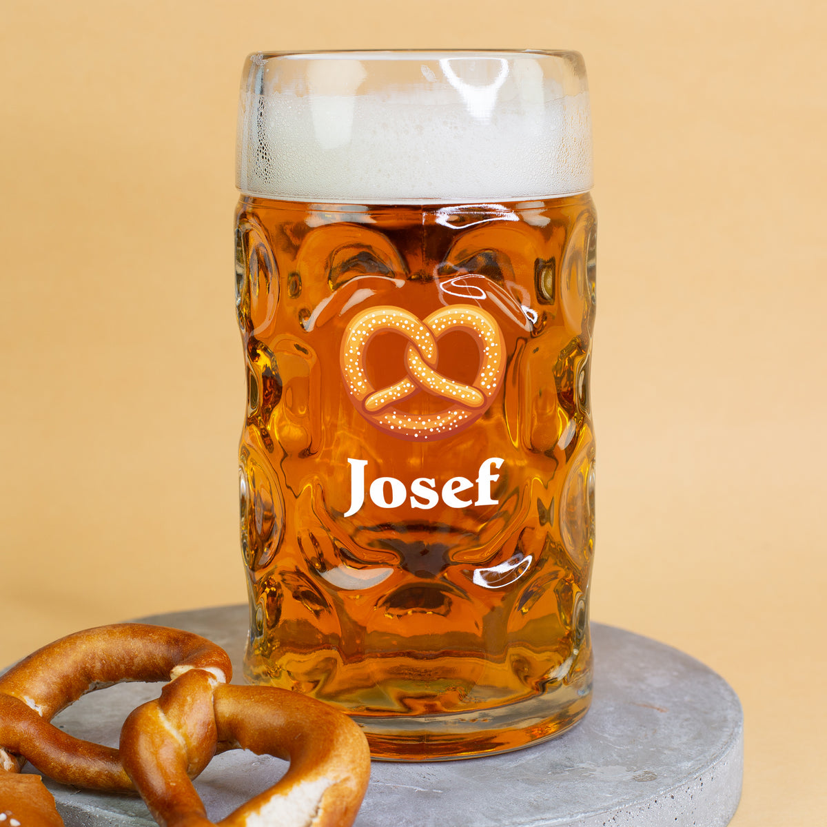 1-Liter-Bierglas mit Brezel auf einer runden Betonplatte
