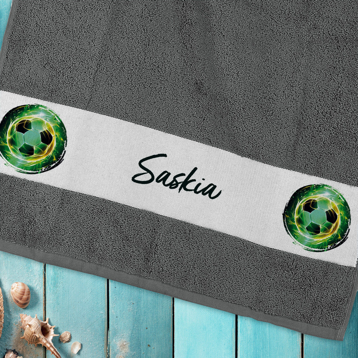Handtuch mit Fußballmotiv und Namensaufdruck „Saskia“ auf Holzuntergrund