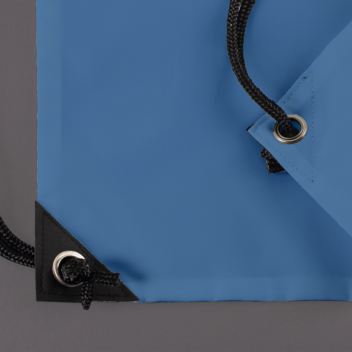 Detailaufnahme der verstärkten Ecken mit Metallösen und Kordelzug des blauen Turnbeutels