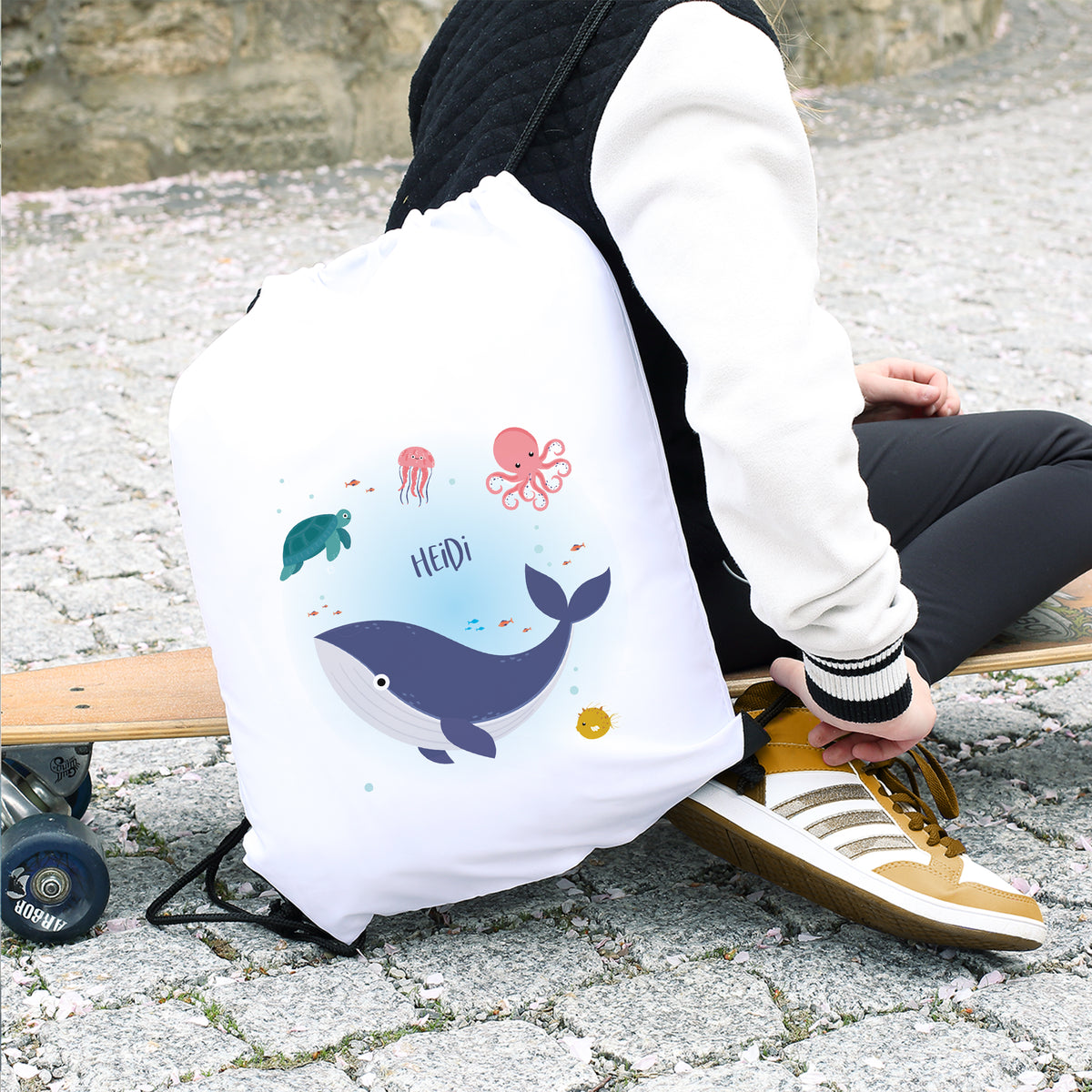 Kind mit weißem Turnbeutel mit Wal-Motiv und Namen Heidi