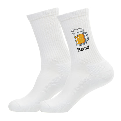 Freigestellte Aufnahme eines Sockenpaares mit Bierkrug-Motiv und Name „Bernd“ – Studioaufnahme auf weißem Hintergrund.