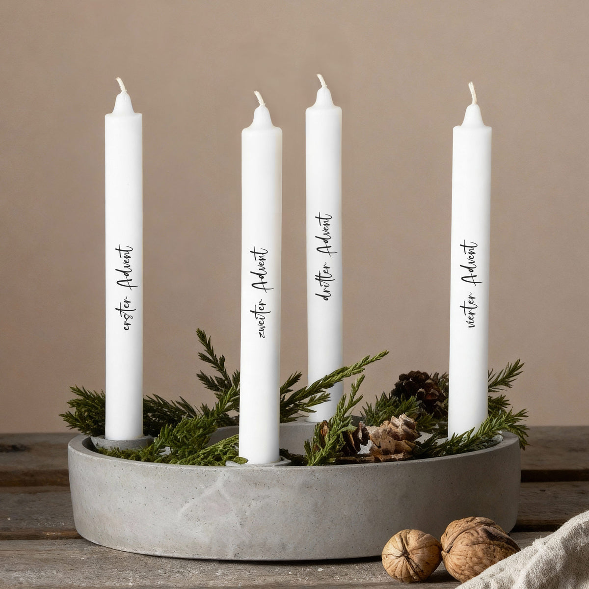 Adventskerzen mit individuellen Texten in modernem Kranz aus Naturmaterialien arrangiert.