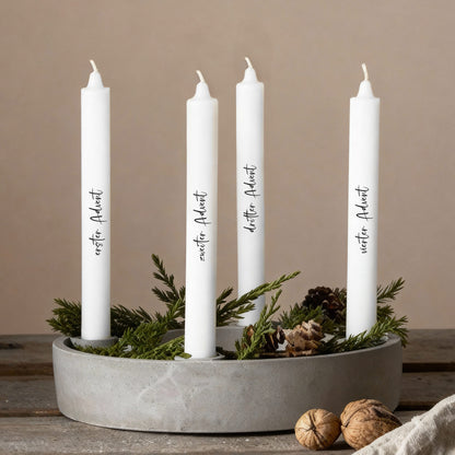 Adventskerzen mit individuellen Texten in modernem Kranz aus Naturmaterialien arrangiert.