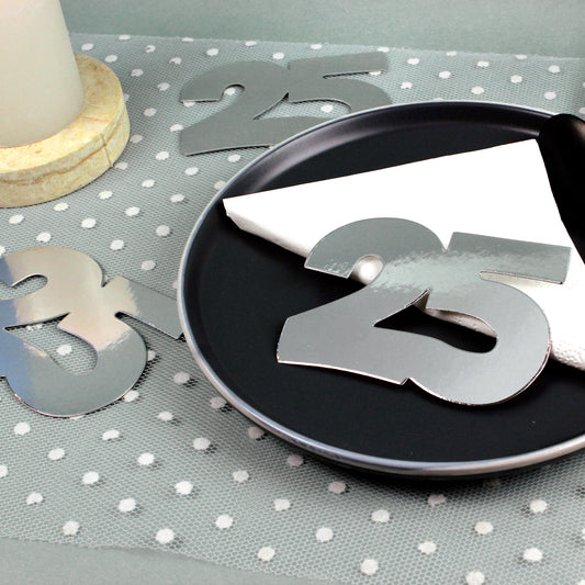 Jumbo-Konfetti Zahl 25 Silber zur Silberhochzeit auf gedecktem Tisch mit Serviette und Kerze