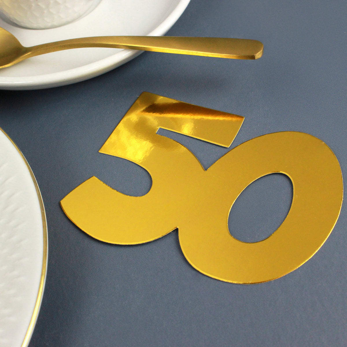 Jumbo-Konfetti Zahl 50 in Gold als Tischdekoration mit Tasse und goldenem Löffel